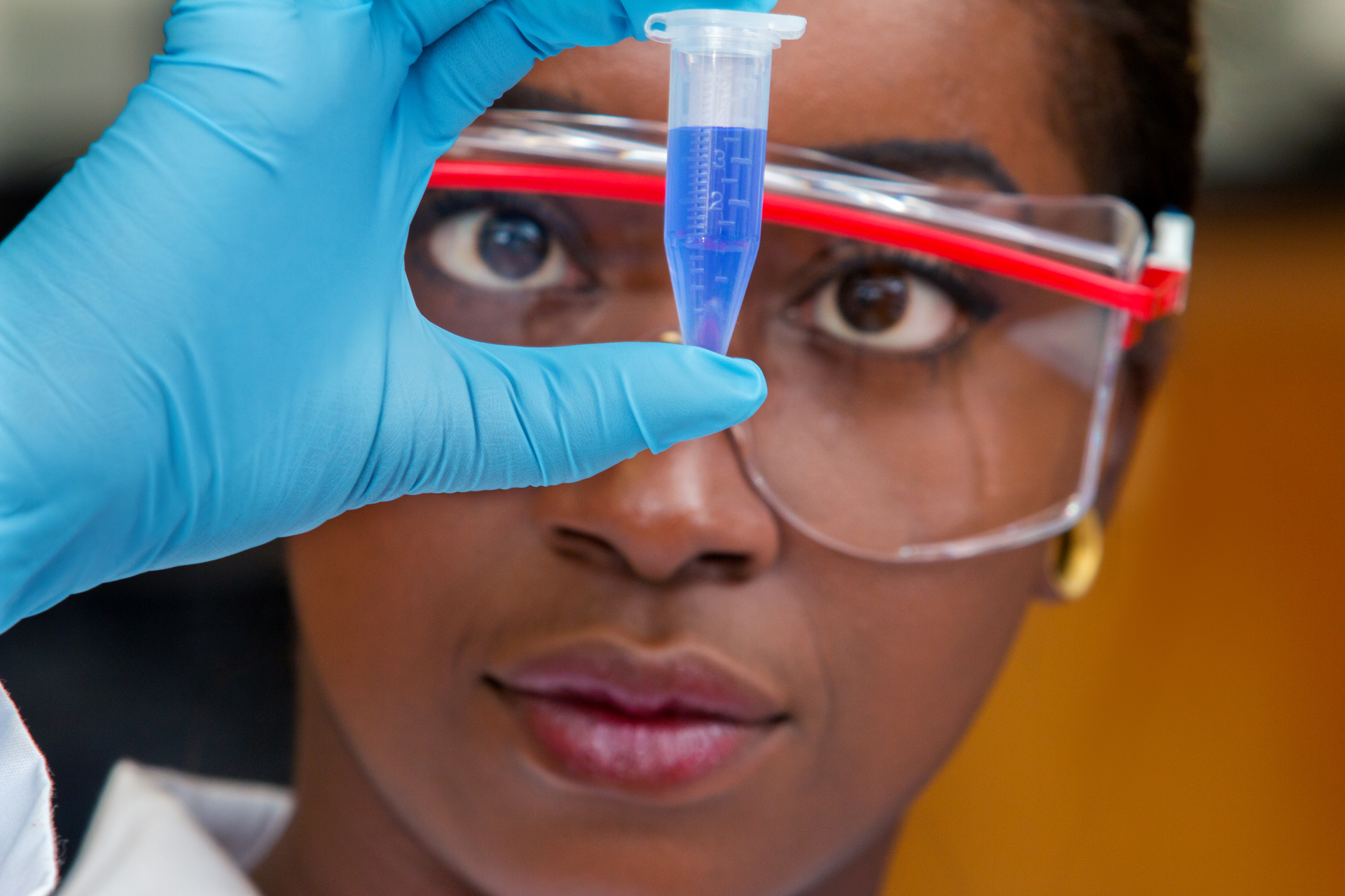 woman in protective glasses looking at vial