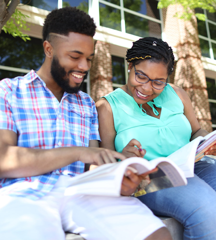 two students outside looking at a book