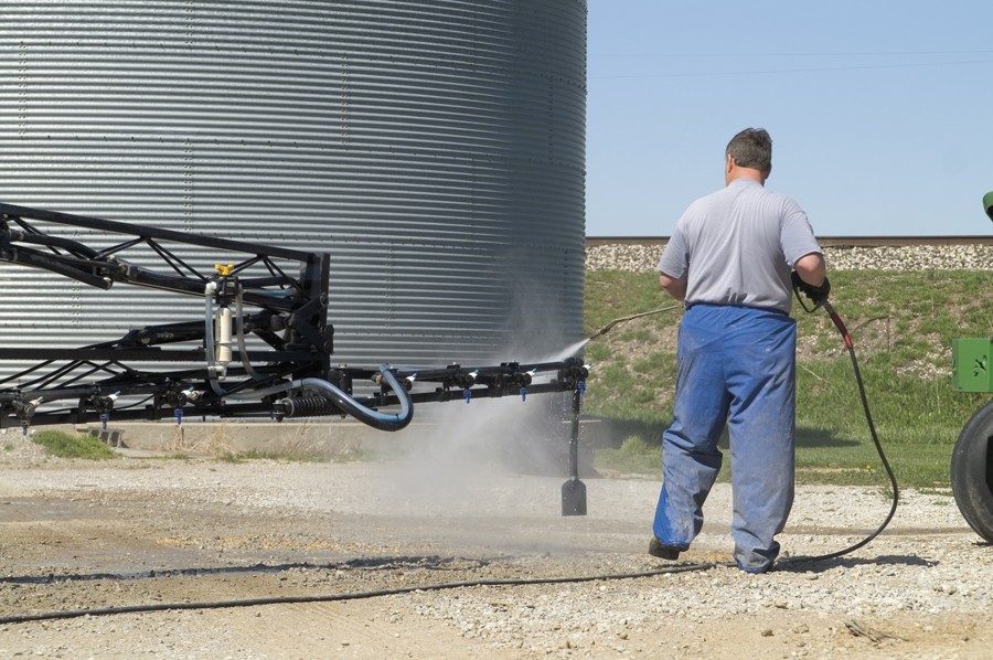 A farmer spraying chemicals on a piece of farm equiptment