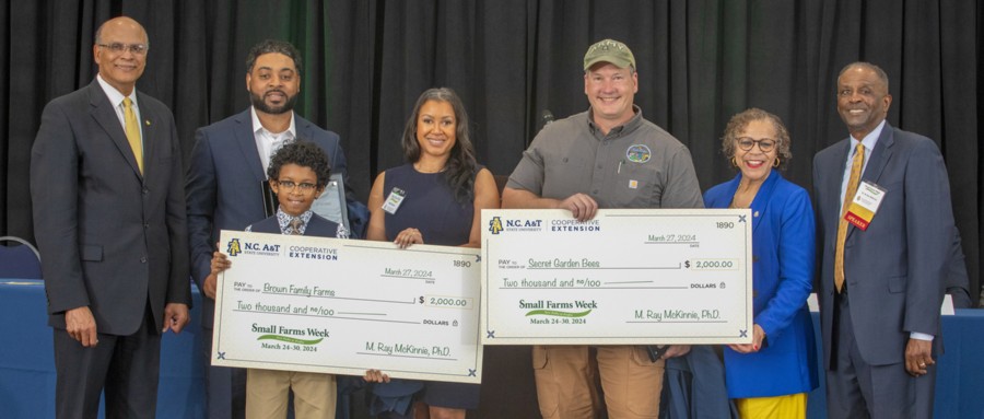 Small farmers of the year standing with a group of university officials holding giant checks