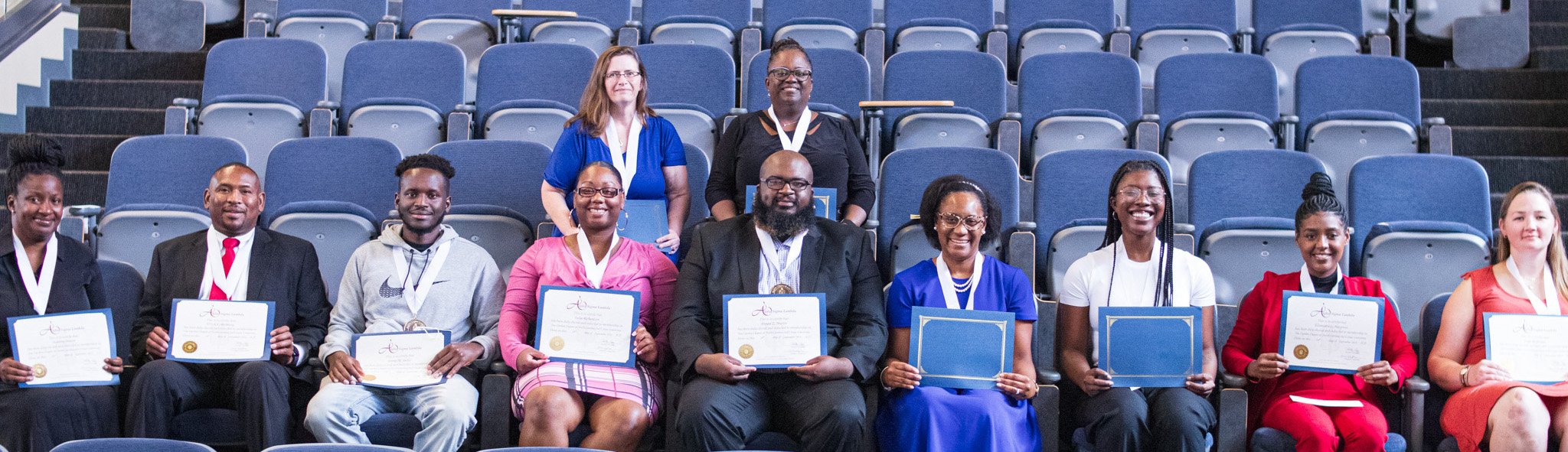 11 inductees seated in auditorium