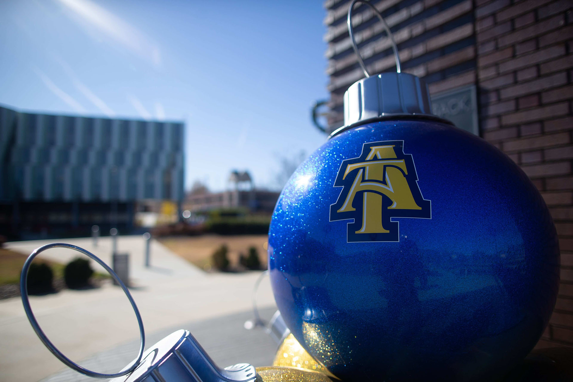 Large blue and gold A&T ornaments stacked beside the Deese Clock Tower and facing Frye Hall