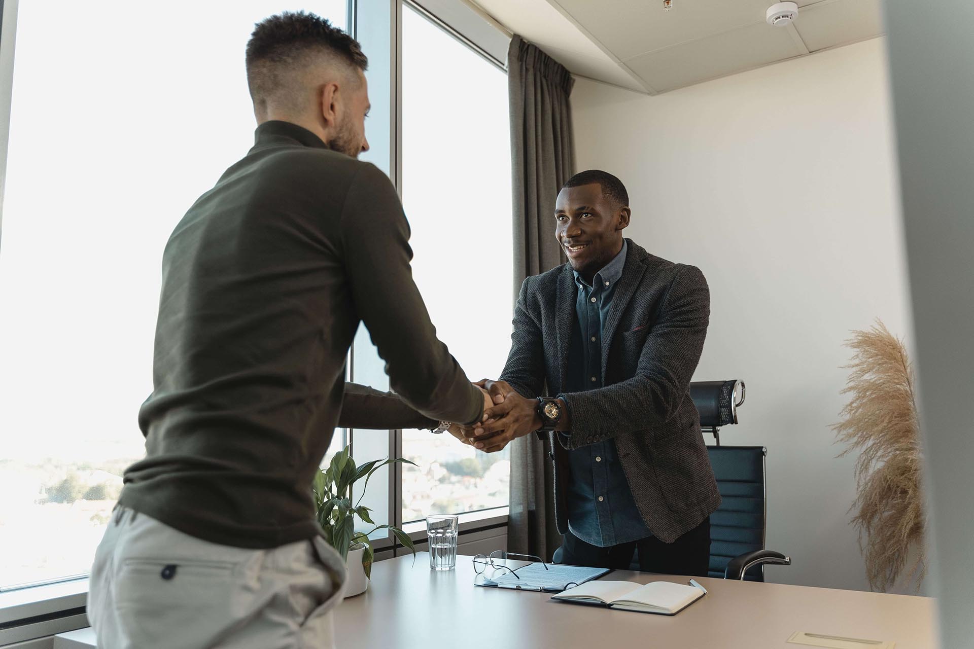 Two men standing and shaking hands over a table