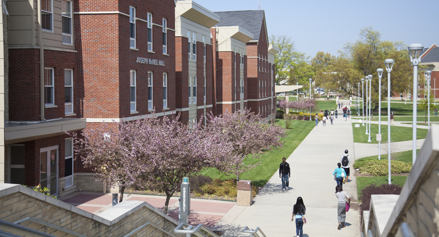 Campus dorm with students walking on sidewalk